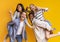 Two international student couples having fun over yellow background