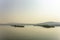 Two islands with green forest in a river misty valley under blue sky, aerial view