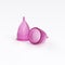 Two isolated pink menstrual cups