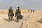 Two Israeli soldiers on the foreground walking on the territory of Masada fortification after prolonged and exhausting military