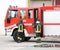 two Italians firefighters descend from fire trucks