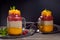 Two jars of layered chia pudding on dark wooden background
