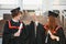 Two joyful students in black academic gowns and caps standing in a library among the bookshelves. Educational concept