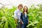 Two joyous agriculturists in protective glasses standing in the hothouse