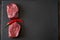 Two juicy, fresh, aged filet mignon steaks on a slate cutting board with a pod of red chili. Top view from an angle, copy space