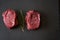 Two juicy, fresh, aged filet mignon steaks on a slate cutting board with a sprig of rosemary on top. Top view from an angle