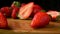 Two juicy ripe strawberries are falling on the wet wooden table