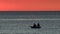 Two Kayak silhouettes fishing from a boat on a peaceful waters at sunset. Golden setting sun and orange sky.