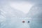 Two kayakers on azure alpine lake shrouded by mist during early winter, Banff N. Park, Canada