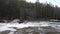 Two kayakers floating on a foamy river.