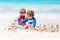 Two kid boys building sand castle on tropical beach of Bora Bora