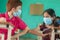 Two kid in medical mask at classroom greeting each other with elbow bumps while maintaining socail distance at school -