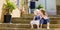 Two kid sisters sitting on stairs in italian town