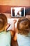 Two kids on the bed having a videochat with father
