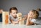 Two kids boy and girl in white t-shirts lie on the floor and play Jenga