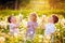 Two kids boys and little baby girl blowing on a dandelion flowers on the nature in the summer. Happy healthy toddler and