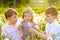 Two kids boys and little baby girl blowing on a dandelion flowers on the nature in the summer. Happy healthy toddler and
