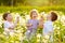 Two kids boys and little baby girl blowing on a dandelion flowers on the nature in the summer. Happy healthy toddler and