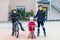 Two kids boys and little toddler girl playing together outdoors. Brothers in safety clothes skating with rollers and