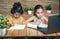 Two kids busy in writing by looking into the laptop during online or virtual class at home - concept of e-learning or distance