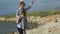 Two kids caucasian boy and girl family playing holding flying kite on sea beach with strong wind