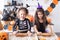 two kids girl in costume of witch, baking cookies, having fun in kitchen, celebrating Halloween