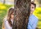 Two kids hiding behind the tree. Young Girl and Boy playing around the tree in park. Portraits of two kids in the park.