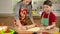 Two kids kneading the dough, making the pizza