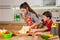 Two kids kneading the thin sheet of dough, making the pizza