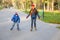 Two kids learning to ride in autumn park on rollerblades