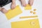 Two kids make natural rolled beeswax candles from pressed beeswax honeycomb sheet at home indoors.