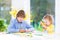 Two kids painting and cutting colorful paper butterflies