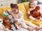 Two kids playing with dolls sitting on sofa at home