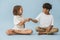 Two kids of roughly the same age sitting on the floor cross-legged