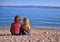 Two kids sitting on beach and looking at horizon