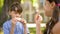 Two kids sitting outdoors the school eating sandwiches