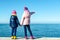 Two kids standing on sea shore, holding hands