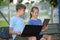 Two kids, teenager boy holding laptop computer and pretty young girl with digital tablet studying together outdoors