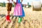 Two kids in traditional Bavarian costumes and red and green rubber boots in wheat field. German children during