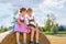 Two kids in traditional Bavarian costumes in wheat field. German children sitting on hay bale during Oktoberfest. Boy