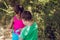 Two kind children doing school tasks and collecting garbage with a plastic bag in the park