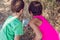 Two kind children doing school tasks and collecting garbage with a plastic bag in the park