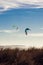 Two kites dance against a light blue sky