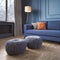 Two knitted poufs near dark blue corner sofa. Scandinavian home interior design of modern living room