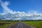 Two-lane asphalt country road, leaving beyond the horizon. Landscape with view of non urban driveway, green ..field, trees and