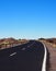 Two lane empty road curving to the horizon in desert landscape