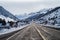 Two lane paved road ascending into snowy mountains