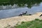 Two large birds walk along the river bank.