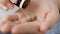 Two large brown-green cylindrical pills fall into palm of hand from pill bottle. Close-up, front view, center