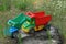 Two large colored toys dump trucks standing on a stump